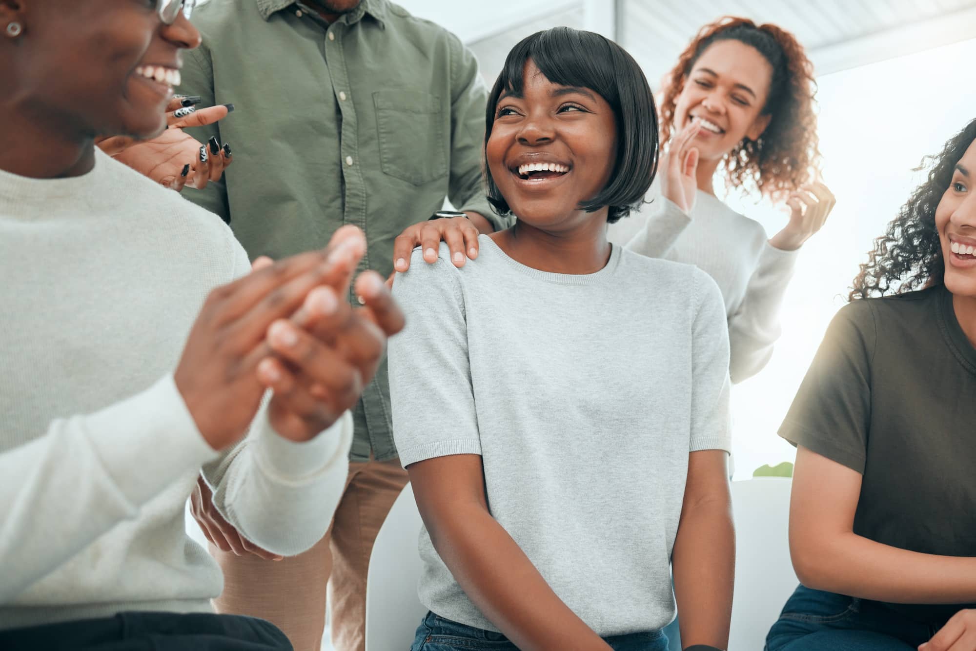 Shot of an attractive young woman sitting while her support group celebrate her success