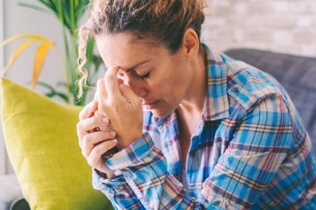 Anxiety and stress disease life concept. Unhappy and worried woman touching his head at home